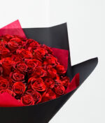 Raudonos rožės juodame įpakavime